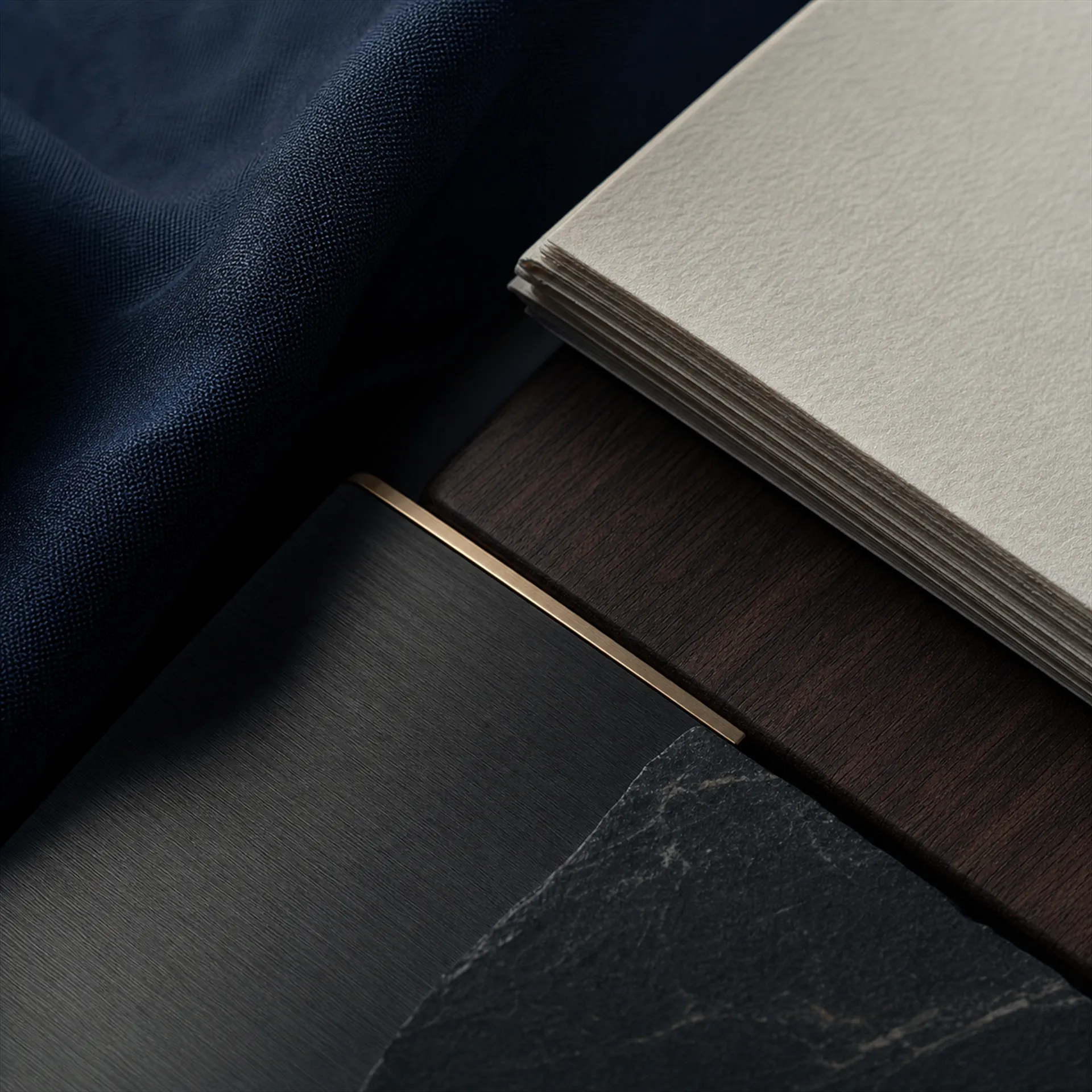 Layered brand materials — navy fabric, dark timber, brass inlay, stone and ivory paper