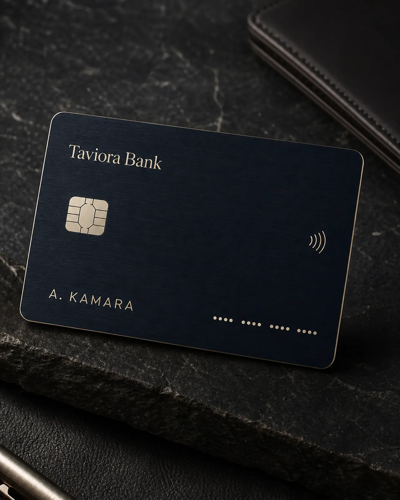 Brushed midnight-blue Taviora Bank card with champagne detailing on dark slate